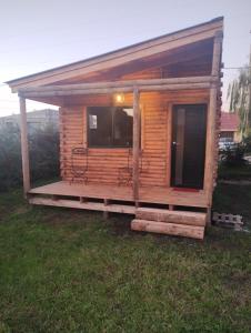 a small wooden cabin with a porch in the grass at Cabañas Olavarría 2 in La Porteña