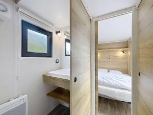 une salle de bain avec un lit, un lavabo et un miroir dans l'établissement Séjour en Tiny House à Jullouville, piscine et parking inclus - FR-1-361A-95, à Jullouville 8 autres photos