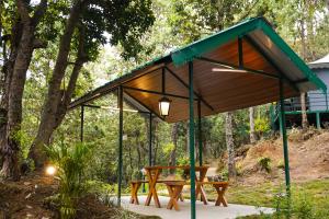 a pavilion with a picnic table in the woods at Buransh Luxury Tent Retreat in Majkhali in Chaubattia
