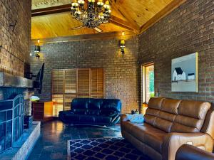 a living room with a leather couch and a brick wall at Upsandowns - Private pool, Spa, and Sauna in Jindabyne