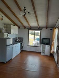 a kitchen with white appliances and a large window at Cabañas Familiares in Huildad