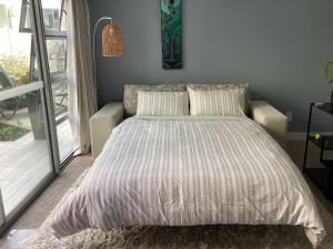a bed in a bedroom with a large window at Lakeside - Minutes to Waikato , Braemar Hospitals in Hamilton +17 photos