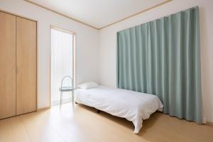 una camera da letto con un letto, una finestra e una sedia di 桜の旅 a Warabi