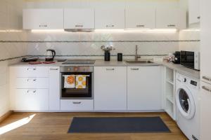 a kitchen with white cabinets and a washer and dryer at Villa Yasmine in Cinisi