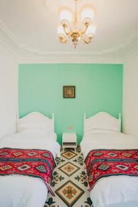 two beds in a room with a chandelier at 一千零一夜喀什古城民宿 Kashgar Ancient City Scenic Area in Kashgar