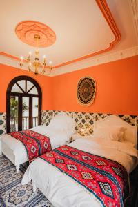 two beds in a room with orange walls at 一千零一夜喀什古城民宿 Kashgar Ancient City Scenic Area in Kashgar