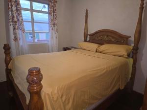 a bedroom with a bed with a wooden frame and a window at Historic Manor in Bridgetown