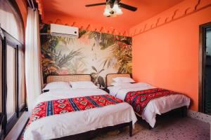two beds in a room with orange walls at 一千零一夜喀什古城民宿 Kashgar Ancient City Scenic Area in Kashgar