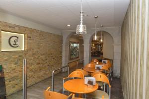 Hostal Linares في ريباديو: مطعم بطاولات وكراسي وجدار من الطوب