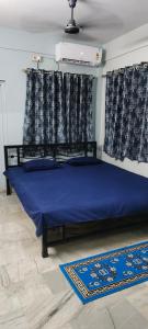 a bedroom with a bed with blue sheets and curtains at The Grasshopper's nest in kolkata