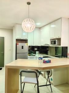 吉隆坡Summer Suites KLCC by CozyNest的厨房配有一张大木桌和吊灯。 更多31张照片