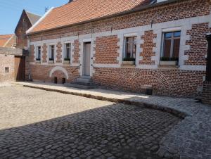 a brick building with a cobblestone street in front of it at Les racines in Haspres