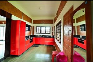 a kitchen with red cabinets and red counters at Ashraya Stay in Kushālnagar