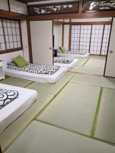大阪Nippori Osaka Nishi-Tengachaya Guesthouse西天下茶屋アパートメント的窗户房间里一排床