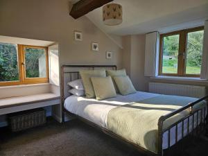 a bedroom with a bed and two windows at Hole House Farm in Millom