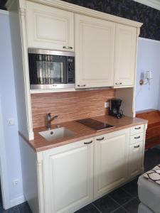 una cucina con mobili bianchi, un lavello e un microonde di Zentrale Ferienwohnung im Kurparkhotel a Bad Rothenfelde