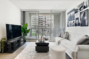墨尔本High-Rise 2BR Luxury Apartment NYC-Inspired Design with Pool Gym Parking and Waterfront Views的带沙发和电视的客厅