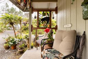 une terrasse couverte avec une chaise et quelques plantes dans l'établissement The Alala at Stained Glass Cottages, à Volcano