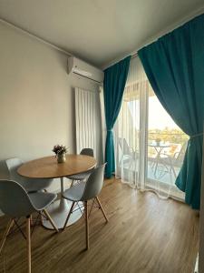 a dining room with a table and chairs and a large window at Apartamente & Studiouri Melia Eforie Nord in Eforie Nord