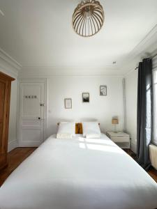 a large white bed in a white bedroom with a chandelier at La Villa Convivium - Chambres privées in Rouen