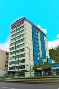 a tall white building with blue windows on a street at Hotel 6 De Diciembre in Quito