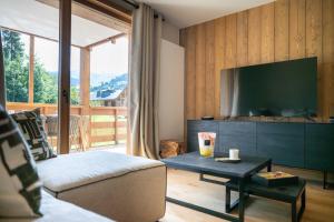 ein Wohnzimmer mit Fernseher, Couch und Tisch in der Unterkunft Exclusive accommodation terrace, parking and pool in Megève