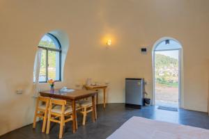 a dining room with a table and two windows at Dome In Doi in Mon Jam