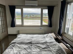 a bedroom with a bed and a large window at countryside FURANO in Nakafurano