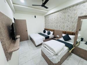 ドワルカにあるhotel shiv palaceのベッド2台とテレビがあるホテルの部屋