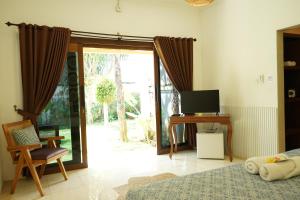 Un dormitorio con una cama, un escritorio y un televisor. en Tattva Uluwatu, Surf & Yoga Retreat, en Jimbaran