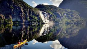two people in a boat on a lake with a waterfall at Birdbox Storehesten in Kvame