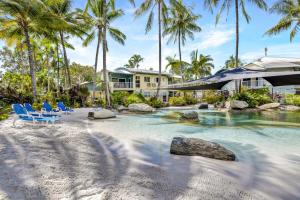 a resort swimming pool with chairs and palm trees at Trinity Escape - Marlin Cove Resort - Trinity Beach in Trinity Beach