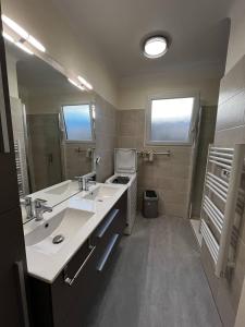 ein Badezimmer mit zwei Waschbecken und einem großen Spiegel in der Unterkunft Maison T4 plain pied climatisée avec une belle terrasse ombragée 6AVR44 in Canet-en-Roussillon