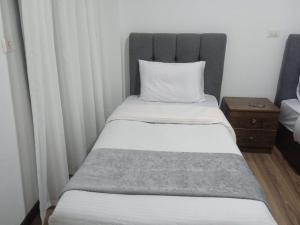 a bed with a headboard and a pillow on it at شقة فندقية بحديقة خاصة رائعة in Madinaty