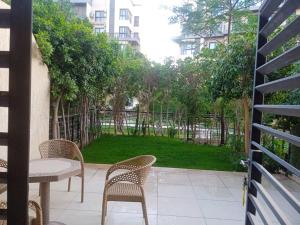a patio with chairs and a table and a garden at شقة فندقية بحديقة خاصة رائعة in Madinaty