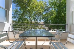 a table and chairs on a balcony with a window at Kipos Resort in Nea Peramos