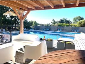 a patio with a table and chairs and a swimming pool at Appartement dans résidence 3 étoiles in Lecci +2 photos