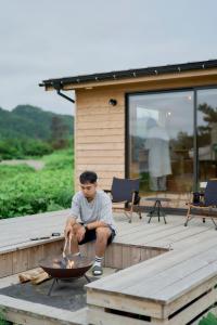 a man sitting on a deck with a fire pit at ist - Sado in Sado