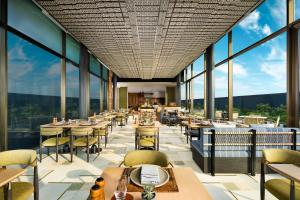 Un restaurante con mesas y sillas y grandes ventanales. en Taj Puri Resort & Spa, Odisha, en Puri