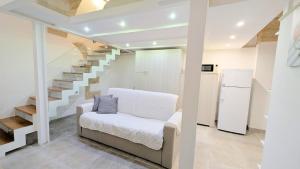 a living room with a white couch and stairs at B&B Corte Regina Esther in Veglie