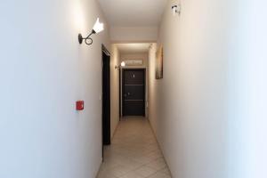 a hallway with a white wall and a black door at Kipos Resort in Nea Peramos
