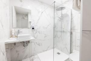 a white bathroom with a shower and a sink at Hotel Santa Maria in Saint-Florent