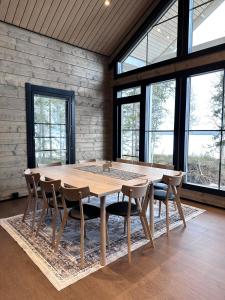 a wooden table and chairs in a room with windows at Villa Norvahovi - Lake view, sauna and wood interior in Rovaniemi