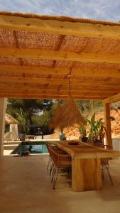 a wooden table with chairs under a wooden roof at Villa Romeo in Sant Jordi