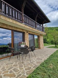 a patio with a table and chairs in front of a house at Dedovina Pakovraće in Čačak