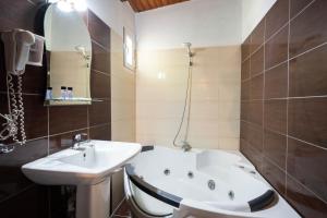 a bathroom with a bath tub and a sink at Kipos Resort in Nea Peramos