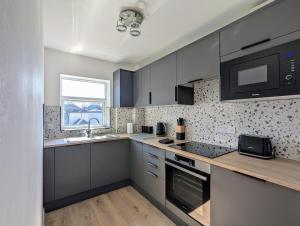 a kitchen with gray cabinets and a sink and a microwave at Saffron Court Apartments - Apt 14 in High Wycombe