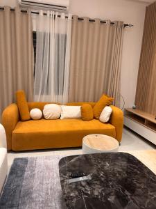 an orange couch in a living room with curtains at Residence Maëlle Fidjrossè togbin avec jardin in Kika +7 photos