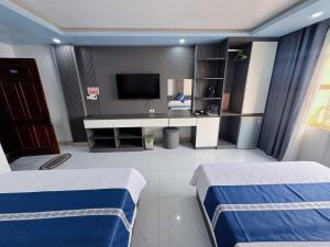 a hotel room with two beds and a television at New Way Hotel in Cat Ba