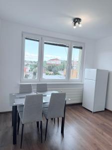 a dining room with a table and chairs and a refrigerator at Pohodlný apartmán s klímou blízko centra Prievidza in Prievidza